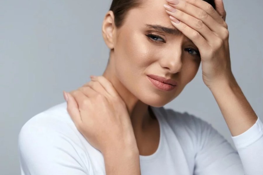 Kobieta zmaga się z silnym bólem głowy.